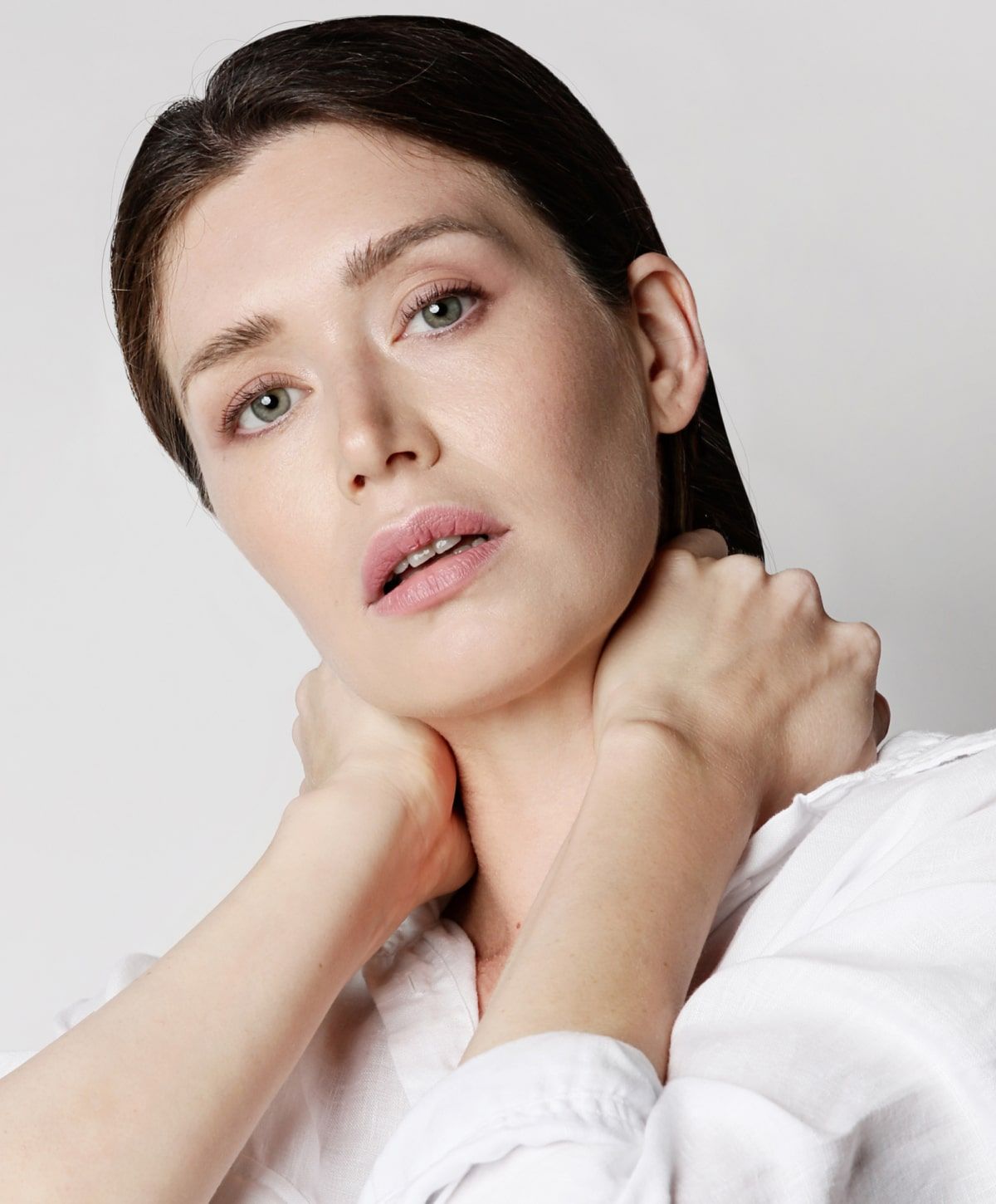 Woman with soft makeup and hands around neck.