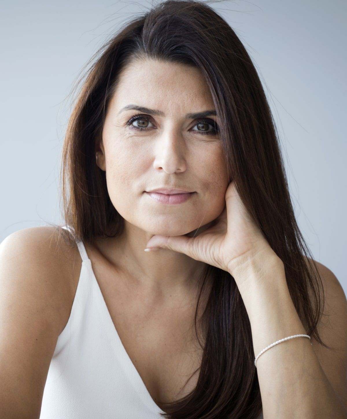 Woman with long hair, resting chin on hand.