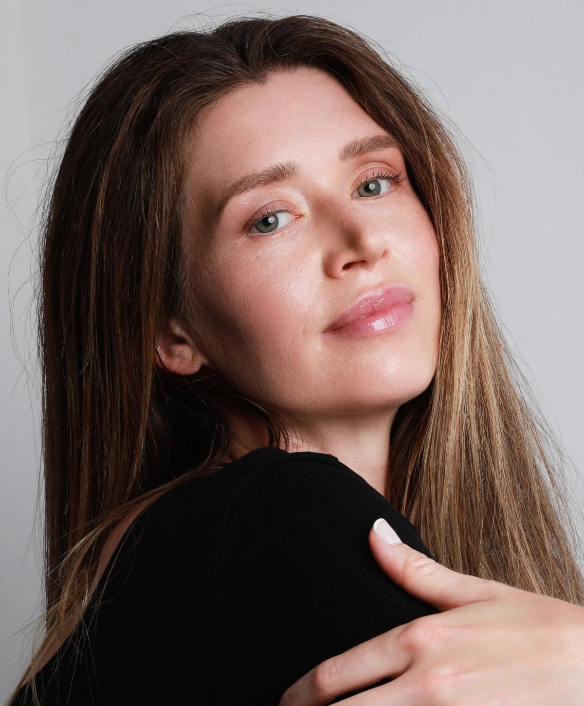 Woman with long hair smiling softly at camera.