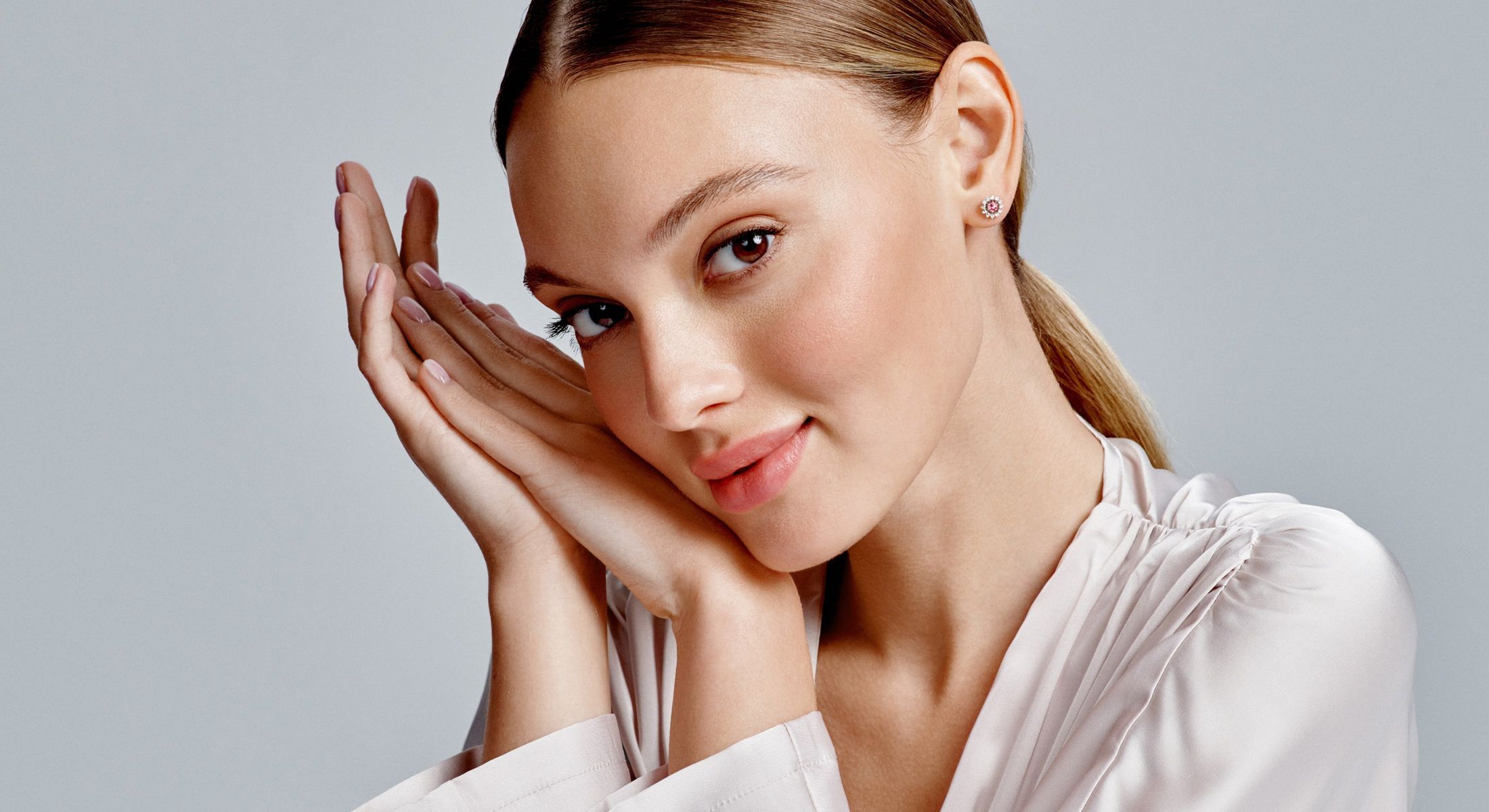 Woman resting hands on her face, smiling gently.