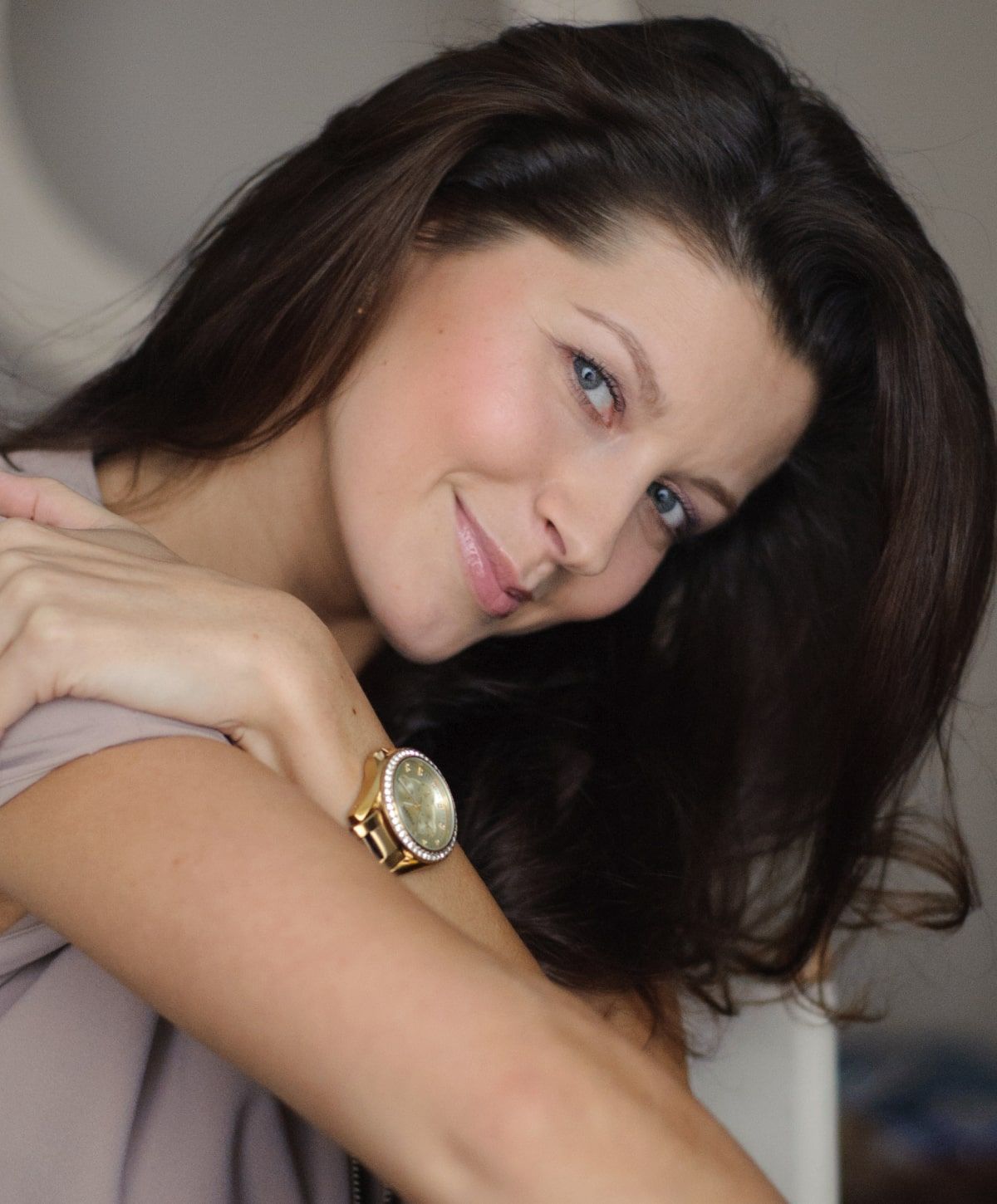 Smiling woman with long hair and wristwatch.