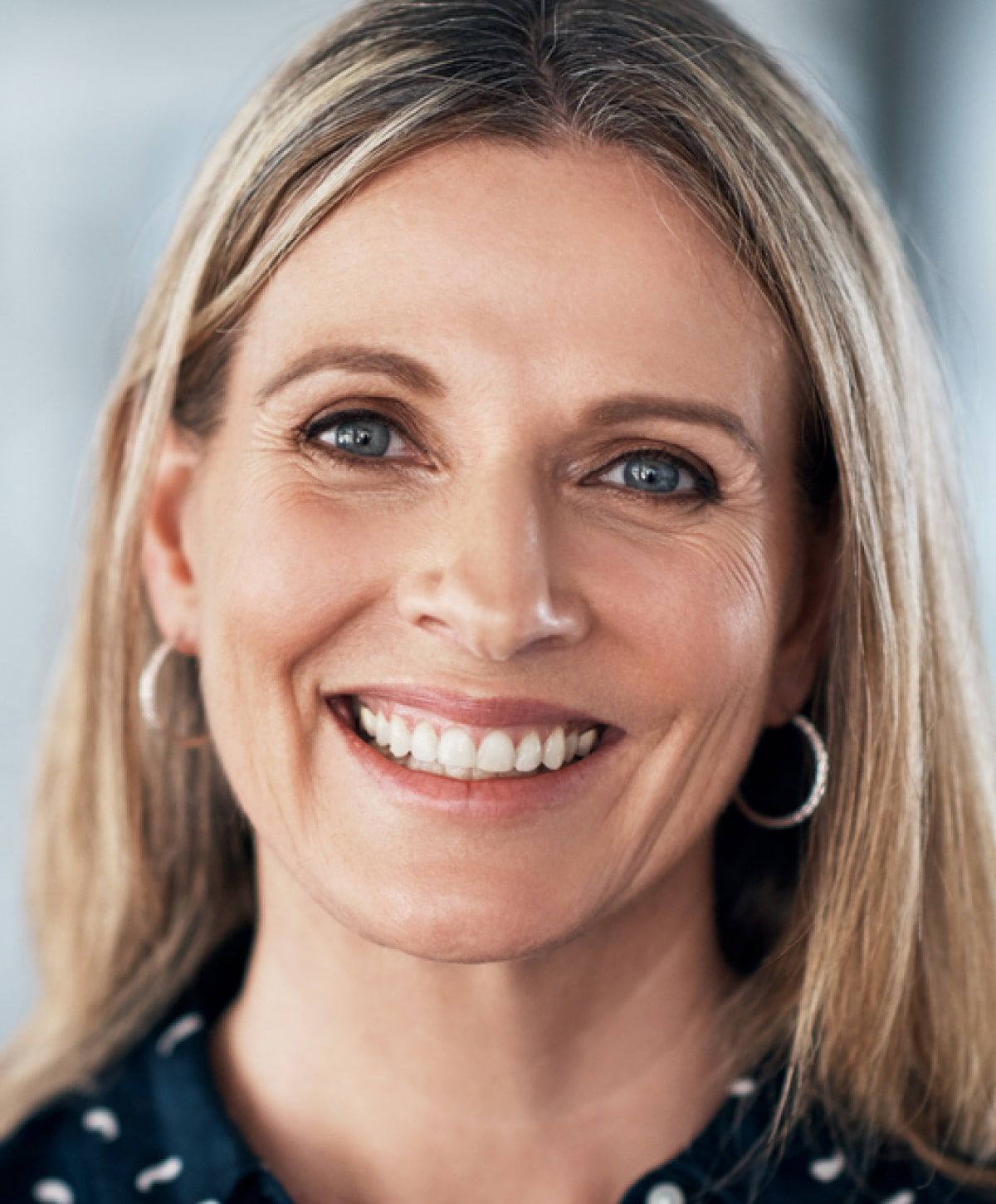 Smiling woman with long hair and earrings.