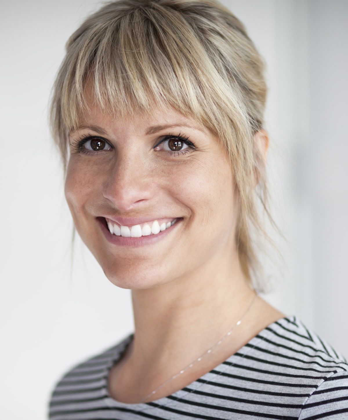 Smiling woman with blonde hair and striped shirt.