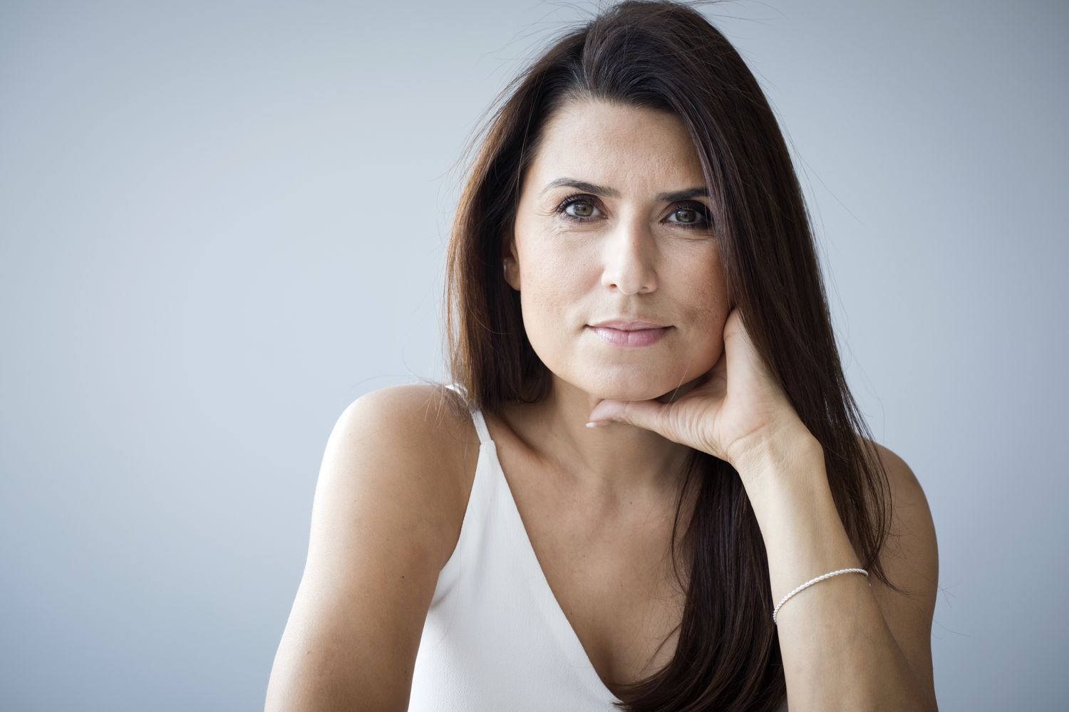 Woman with long hair resting chin on hand