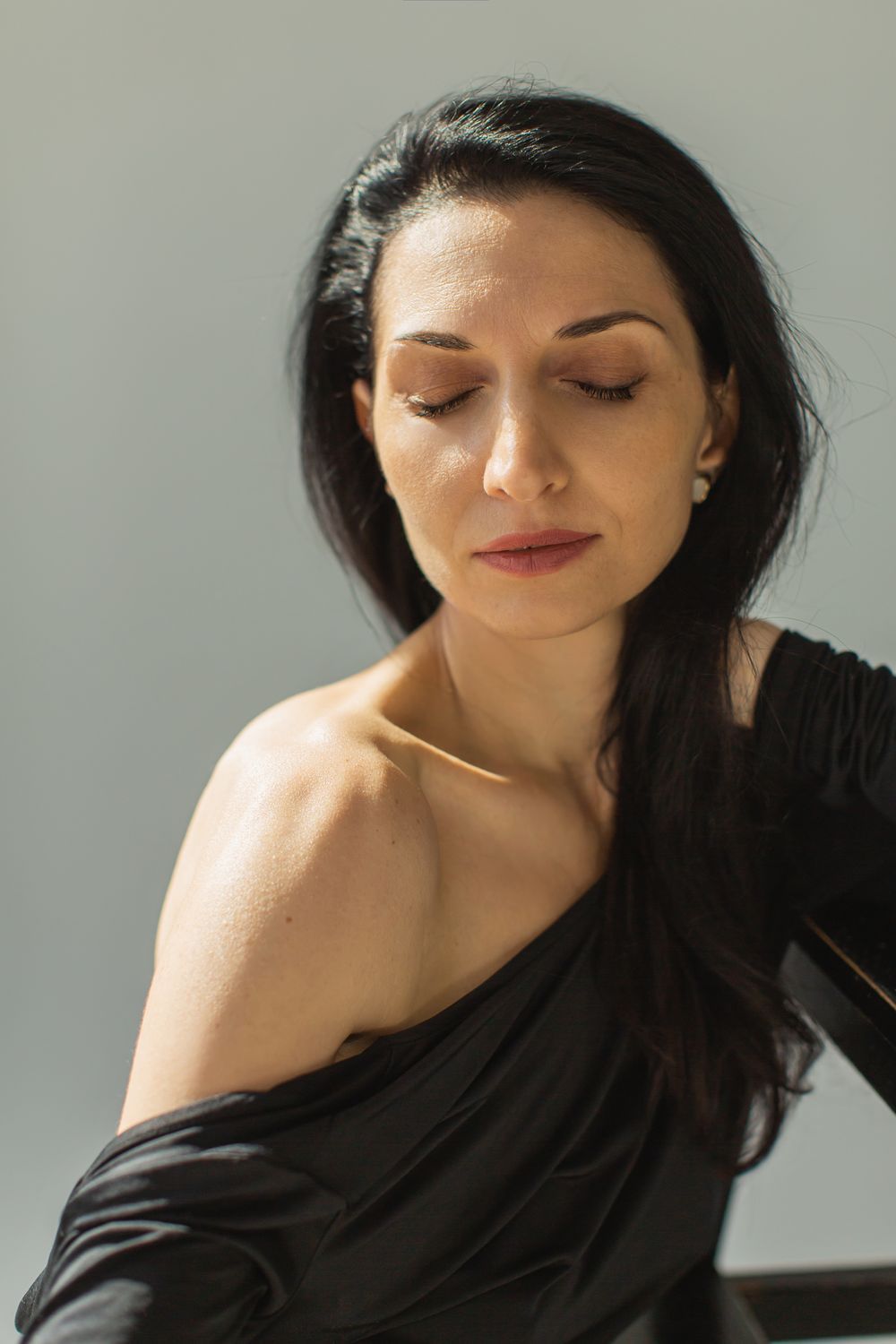 Woman with closed eyes in soft lighting.