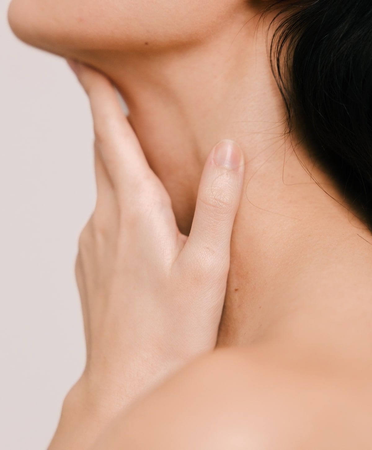 Close-up of hand touching neck gently.