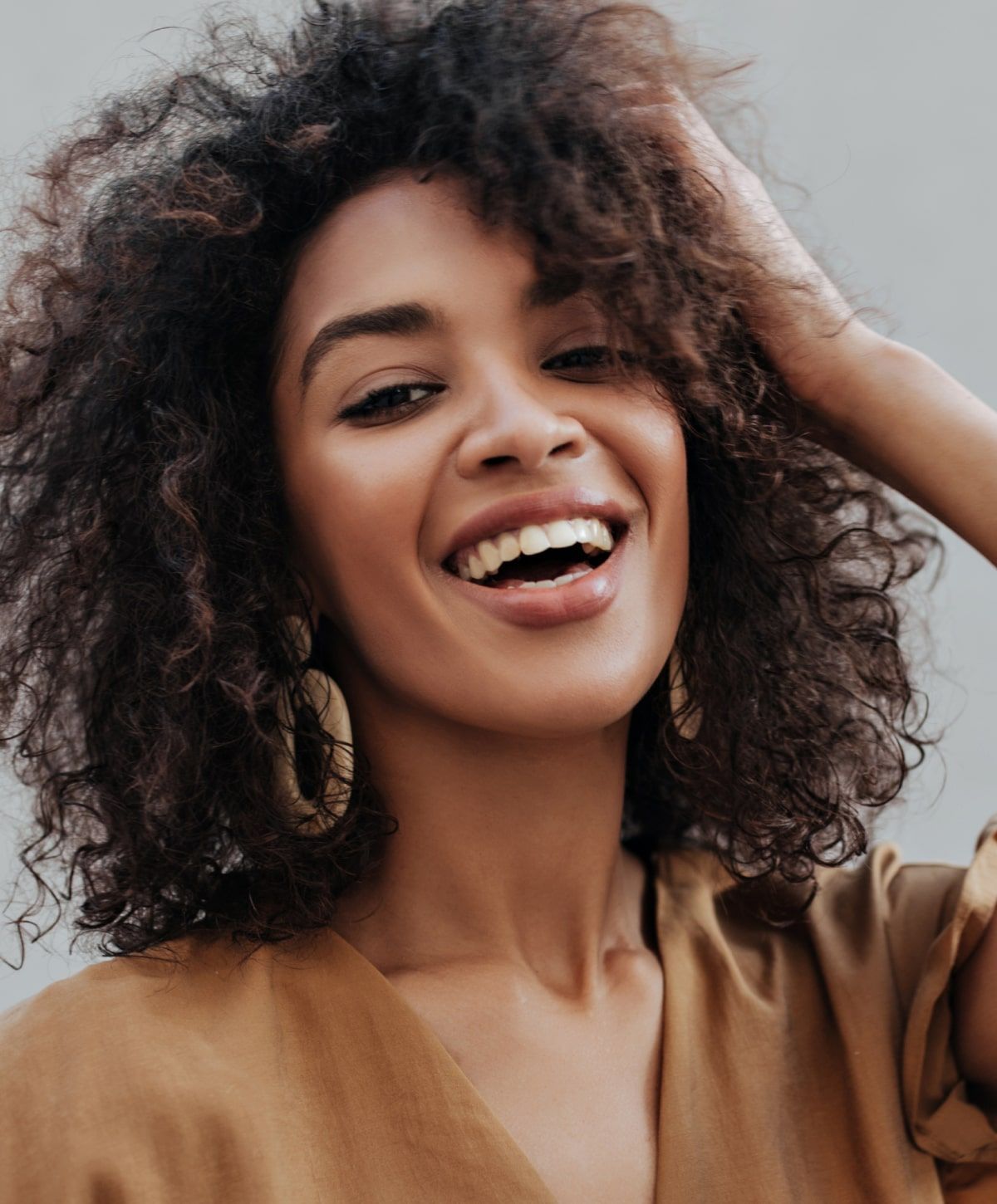 Smiling woman with curly hair and earrings.